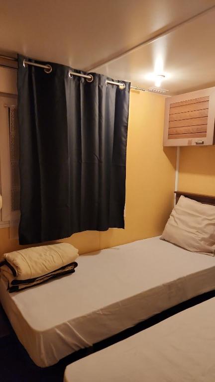a bed in a room with a black curtain at Mobil home 6 personnes Forêt des landes in Mimizan