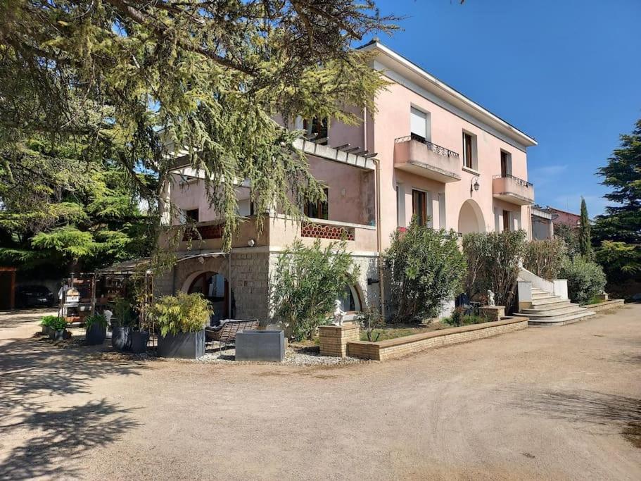 duży różowy budynek z drzewami przed nim w obiekcie Loft ravissant avec jacuzzi et parc w Orange