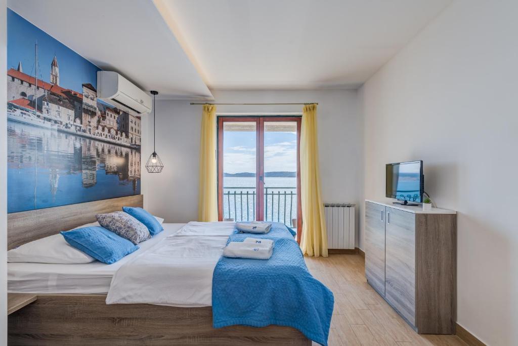 een slaapkamer met een groot bed en een televisie bij Apartments G in Trogir