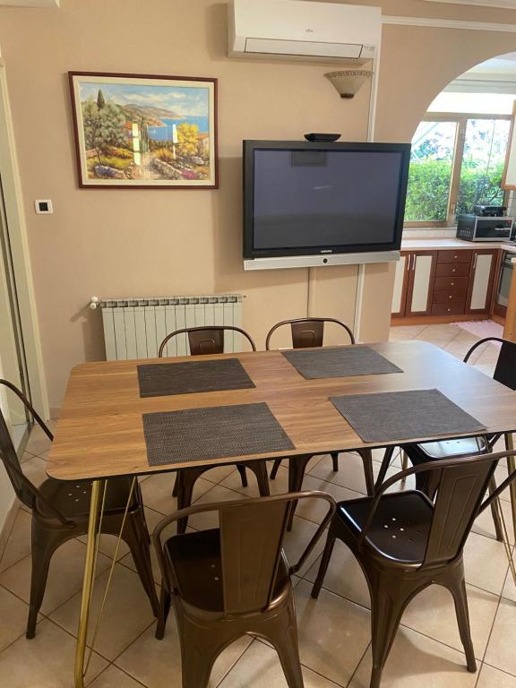 a dining room table with chairs and a flat screen tv at Apartments Oliva in Poreč