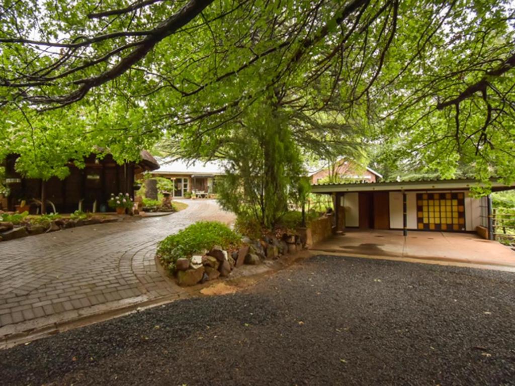 una entrada frente a una casa con un árbol en Rooiland Clarens en Clarens