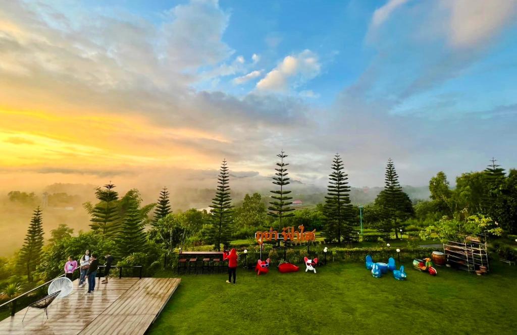 un grupo de personas de pie en un parque con una puesta de sol en Phuyafahsai The Resort Khao Kho en Khao Kho