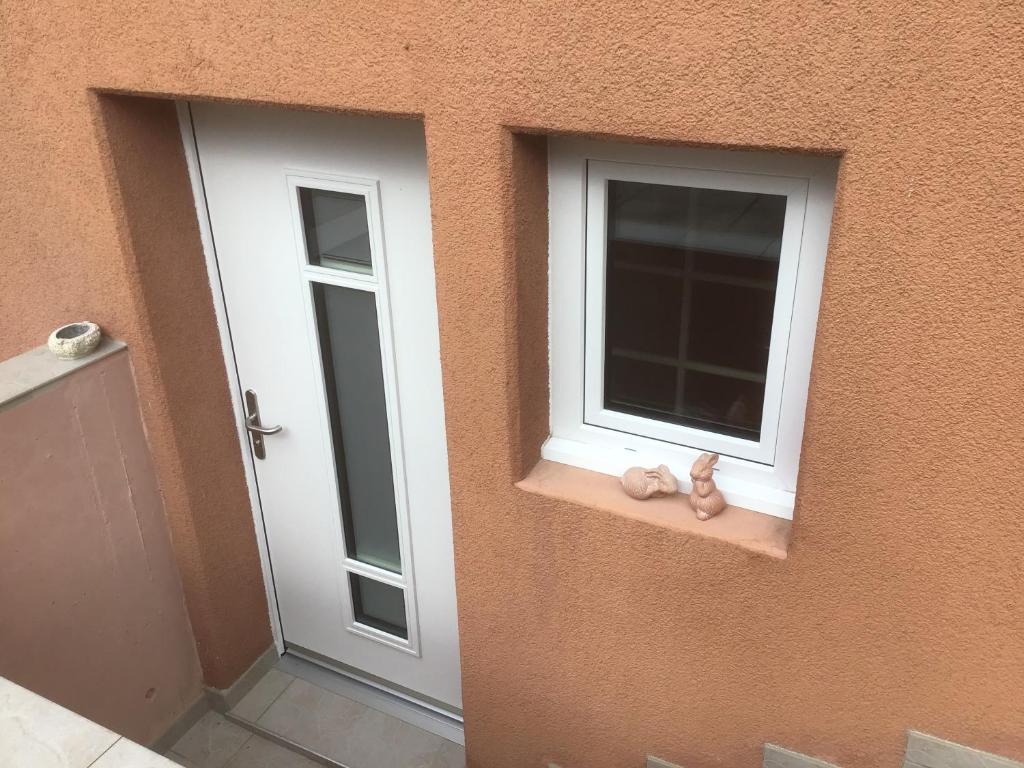Duas janelas com um urso de peluche sentado no peitoril da janela. em Les Ouches em Saint-Blaise