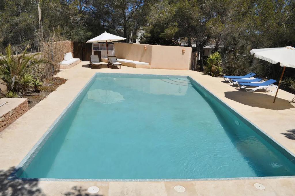 ein blauer Pool mit zwei Stühlen und einem Sonnenschirm in der Unterkunft La Madrugada Formentera by Tentol Hotels in Sant Ferran de Ses Roques