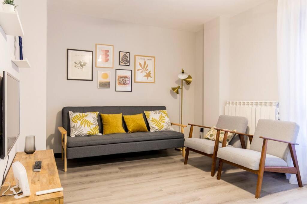 sala de estar con sofá negro y almohadas amarillas en Castrillo 4 Apartamento Acogedor, en Zaragoza