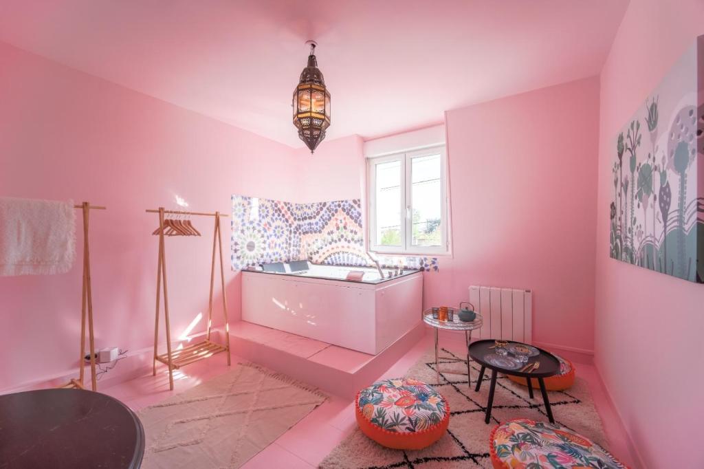 une salle de bains rose avec une baignoire et une fenêtre dans l'établissement Desert de Ouarzazatte paris orly, à Vigneux-sur-Seine