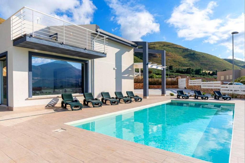 - une piscine avec des chaises et une maison dans l'établissement Villa Sikania Seaview Scopello, à Castellammare del Golfo