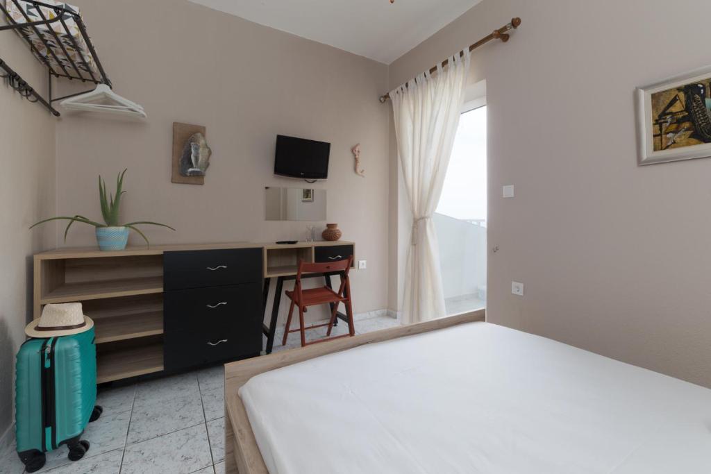 a bedroom with a bed and a desk and a television at Cosy Fourka Beachfront apartment in Skála Foúrkas