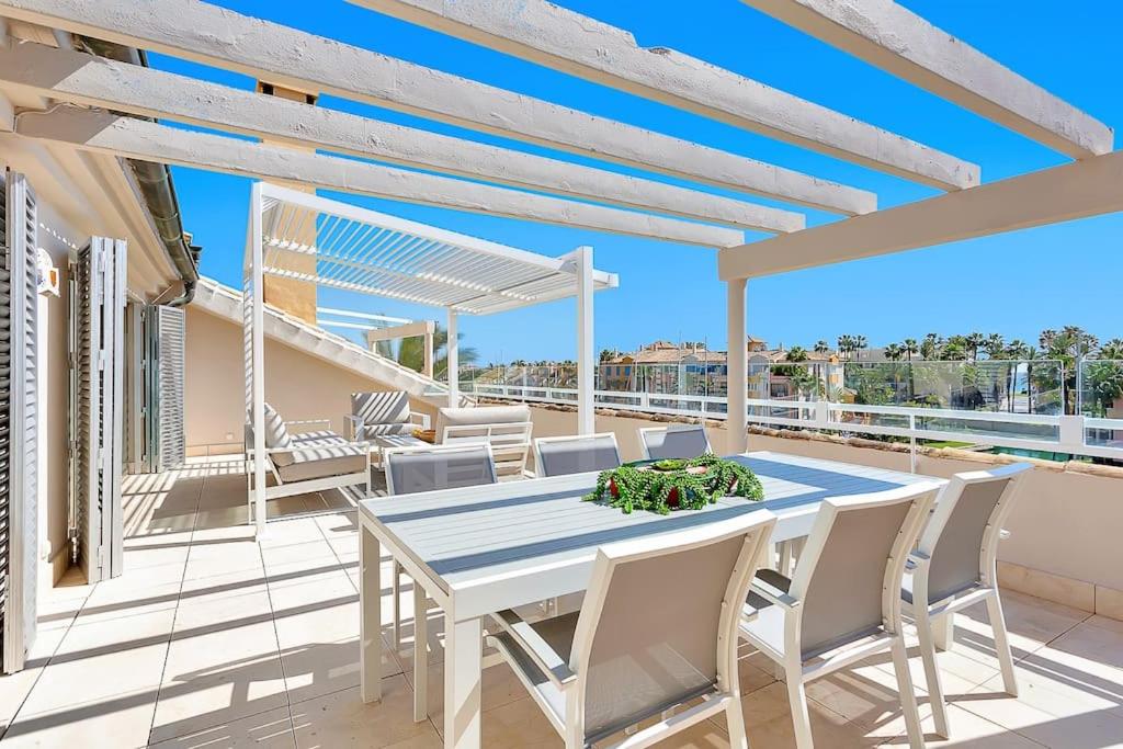 eine Terrasse mit einem Tisch und Stühlen auf dem Balkon in der Unterkunft YOLO Spaces - Sotogrande - Ocean View Penthouse in San Roque