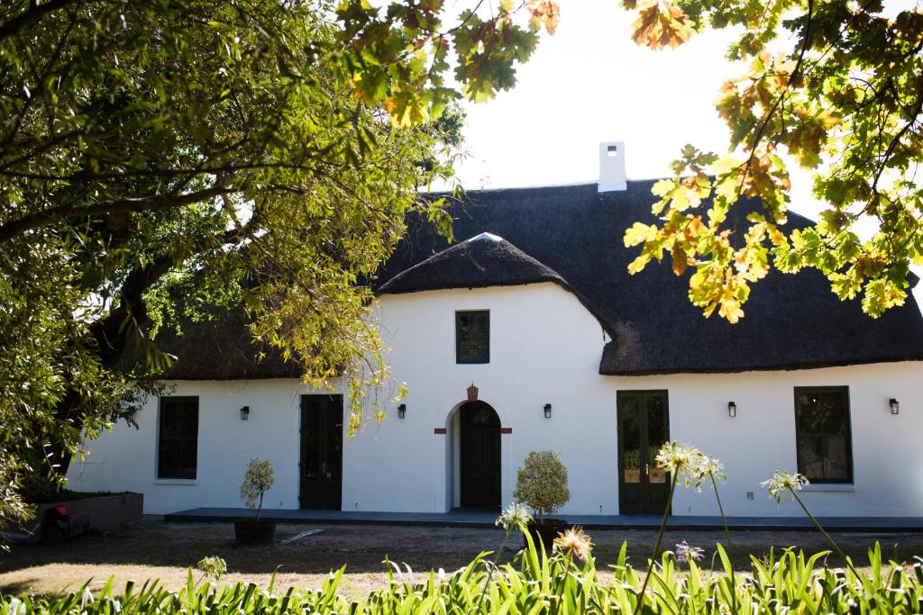 une maison blanche avec un toit de chaume dans l'établissement Manley Wine Estate, à Tulbagh