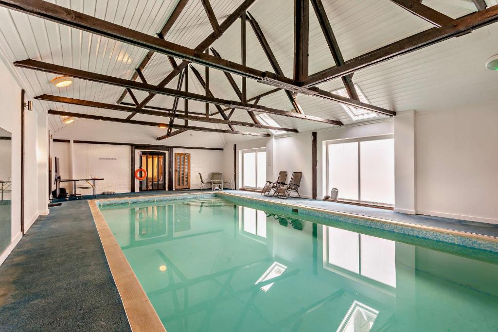 a large swimming pool with blue water in a building at 2 Bed Barn conversion in Tibenham