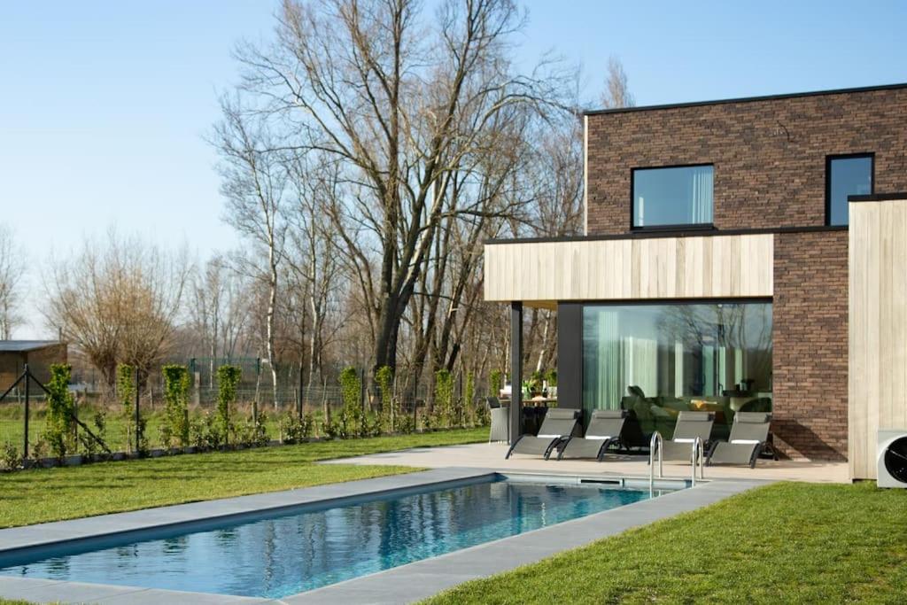 a house with a swimming pool in front of it at Villa Steedje in Jabbeke