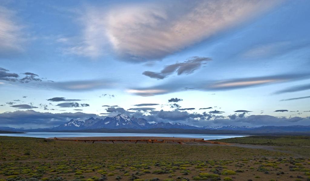 un cielo nublado sobre un cuerpo de agua con montañas en Tierra Patagonia Hotel & Spa, en Torres del Paine