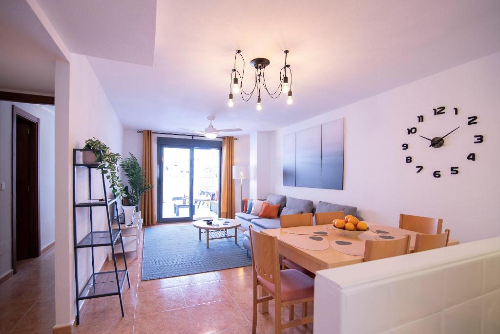 uma cozinha e sala de estar com uma mesa e um relógio em El Patio - Just 170m from El Campello beach em El Campello