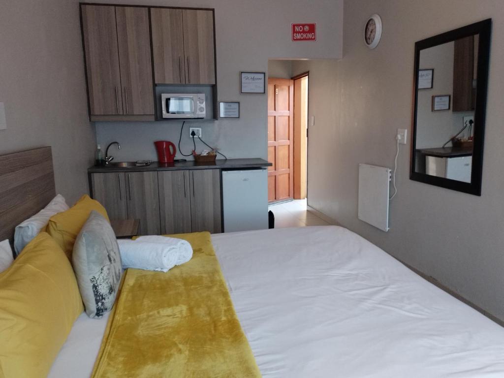 um quarto com uma grande cama branca e uma cozinha em Tokelo Guesthouse Emalahleni em Witbank