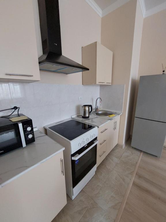 a small kitchen with a stove and a refrigerator at Жк Metropole 2х комнатная in Almaty