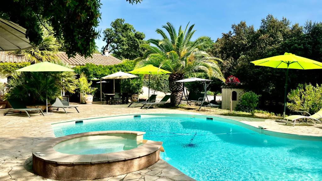 una piscina con ombrelloni in un cortile di Santolines en Provence a Piolenc