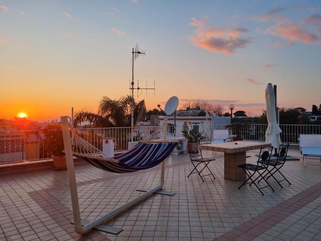 a hammock on a roof with a table and a sunset at Bella D'Estate - 10 minutes from the beach in Ischia