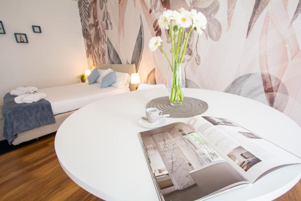 a white table with a book and a vase with flowers at Appartamento Anastasia in Verona