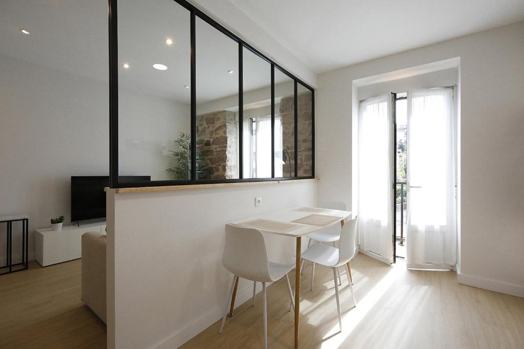 uma sala de jantar branca com uma mesa e cadeiras brancas em Apartment in Donostia well connected downtown em Pasajes Ancho