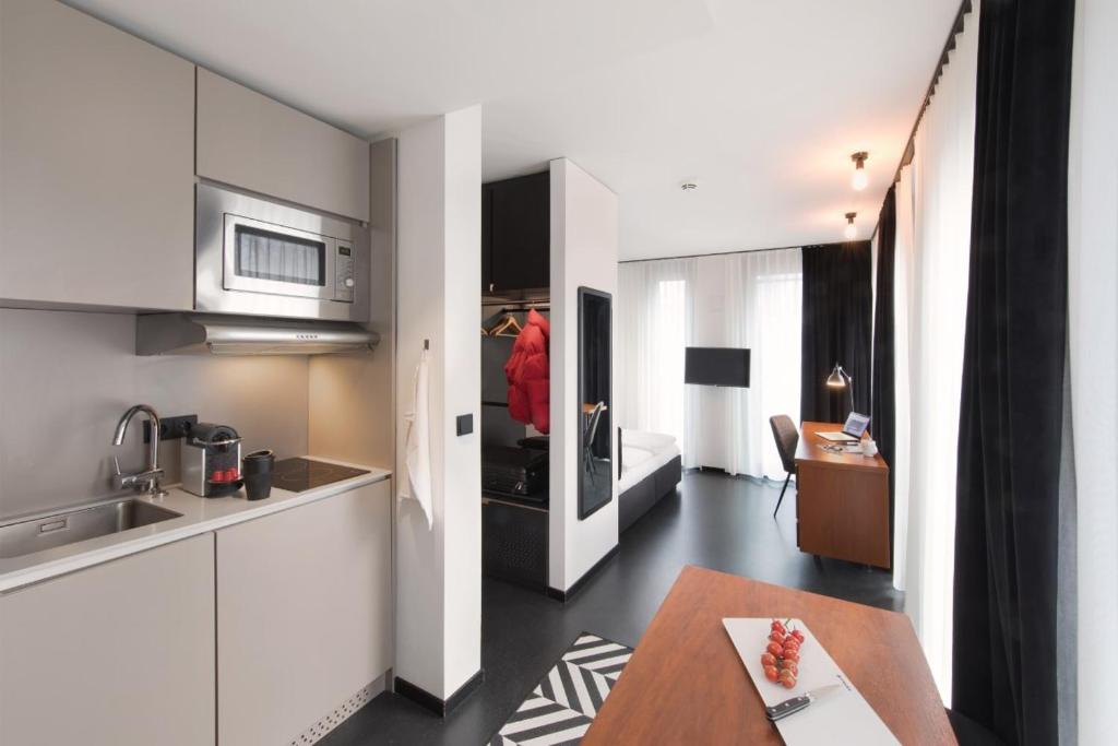 una cocina con armarios blancos y una mesa en una habitación en Brera Serviced Apartments Munich Schwabing en Múnich