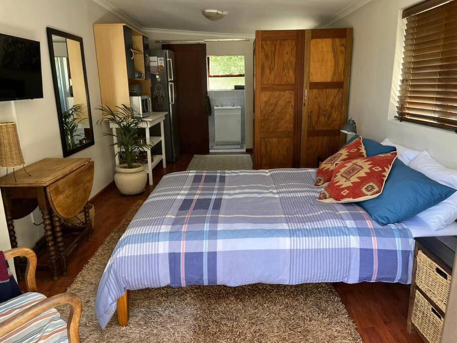 a bedroom with a bed with blue pillows at Pinchushion Cottage Fish Hoek in Fish hoek