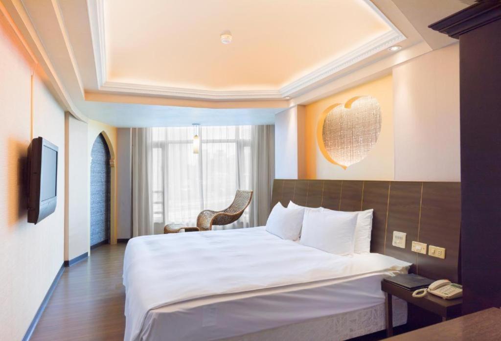 ein Hotelzimmer mit einem großen Bett und einem TV in der Unterkunft Bitan Hotel in Xindian