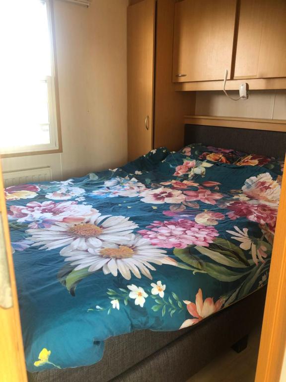 uma cama com um edredão floral num quarto em 17e straatje em Elburg