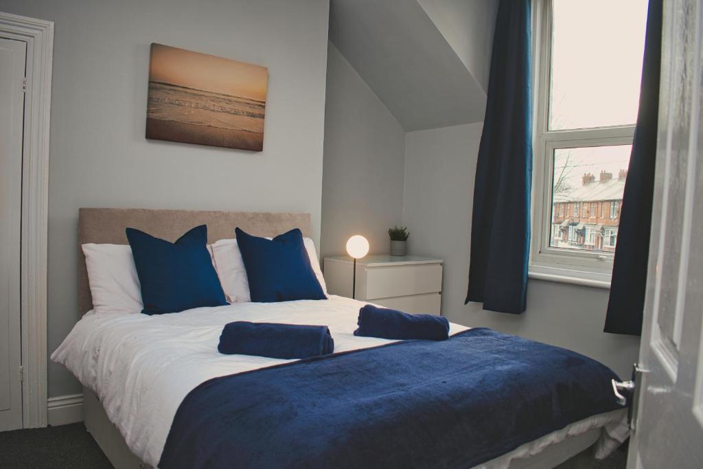 um quarto com uma cama grande e almofadas azuis em Cosy 2 Bedroom Flat in Sunderland em Sunderland