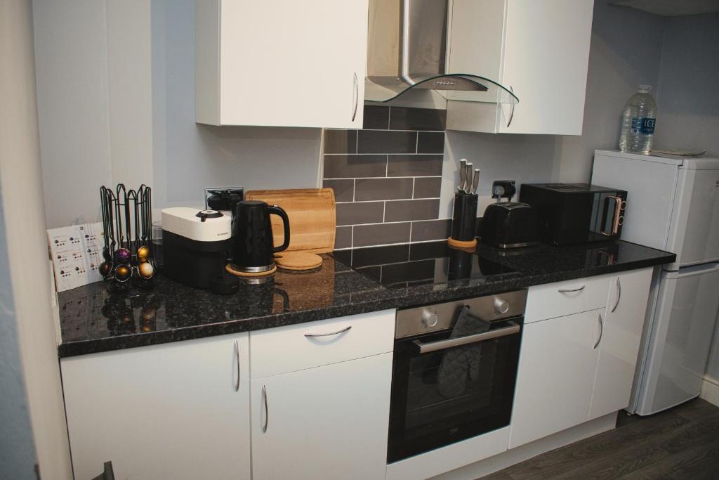 a kitchen with white cabinets and a black counter top at Cosy 2 Bedroom Flat in Sunderland in Sunderland