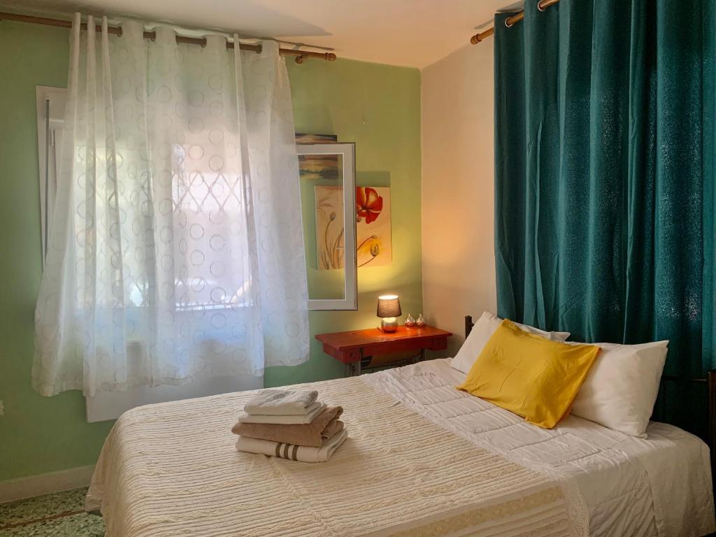 1 dormitorio con 1 cama con cortinas verdes y toallas en lovely place with veranda (Grande), en Larisa