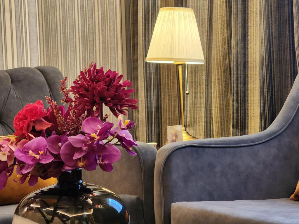 un jarrón lleno de flores púrpuras sentado junto a una silla en Shaty Alhayat Hotel Suites en Yeda