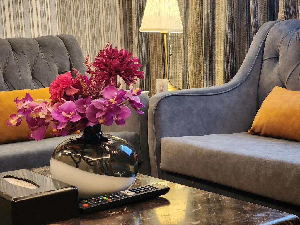 شاطيء الحياه للشقق الفندقية في جدة: غرفة معيشة مع مزهرية مع الزهور على طاولة