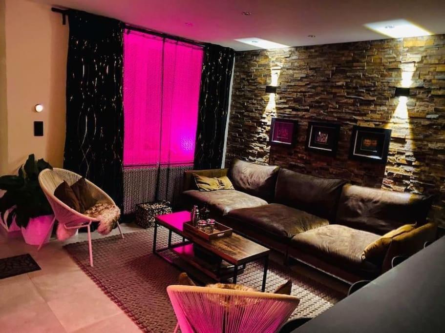 sala de estar con sofá e iluminación rosa en Superbe appartement chic et design, en Seraing