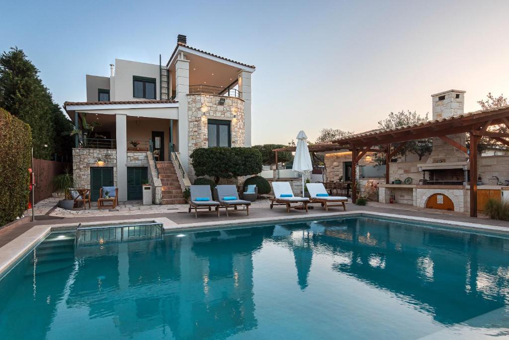 uma piscina com duas cadeiras e uma casa em Antonia Blue Villa em Mourniaí