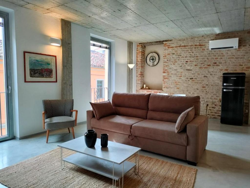a living room with a brown couch and a table at Recinto Nobili 1-private parking su richiesta in Asti