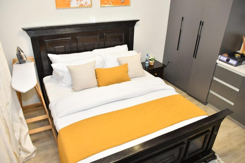 Bett mit orangefarbenen und weißen Kissen in einem Zimmer in der Unterkunft Sky Studio in Nairobi