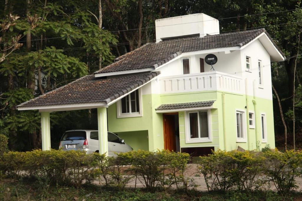 a yellow and white house with a car parked in front at Kodai Elegance in Kodaikānāl