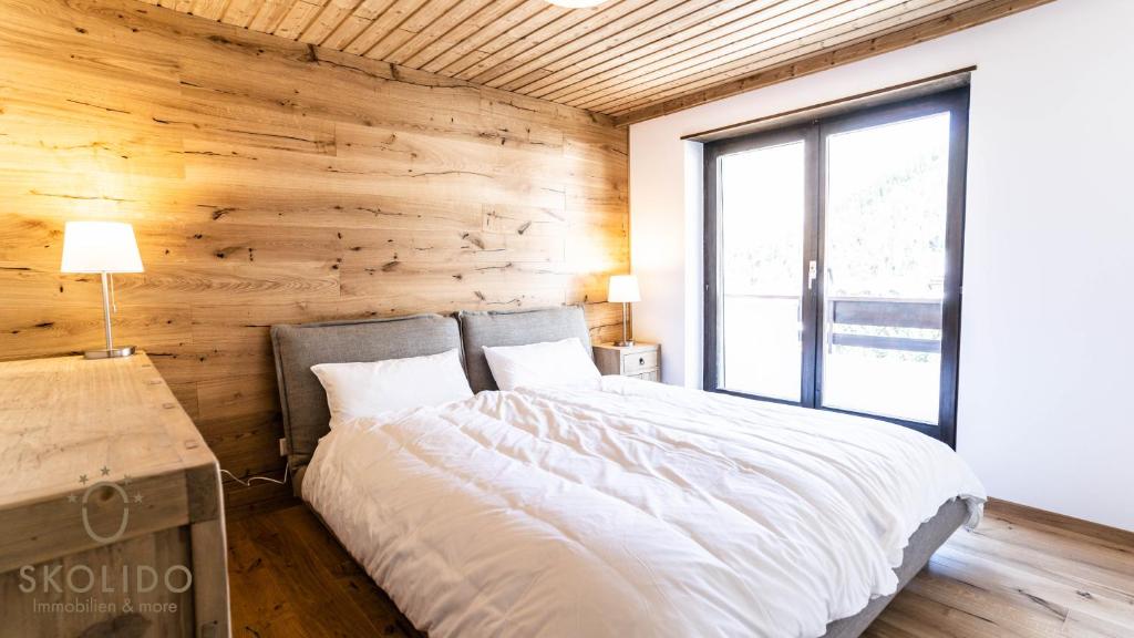 a bed in a room with a wooden wall at Haus Camillo in Saas-Fee