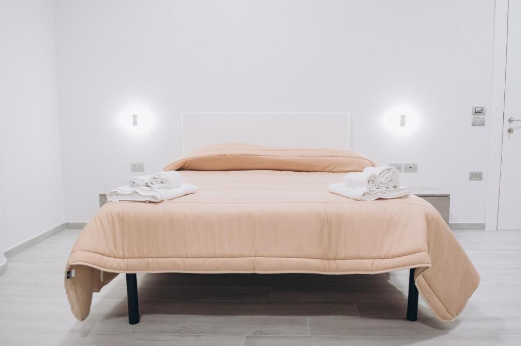 Una cama en una habitación blanca con dos toallas. en Prestige, en Trevico
