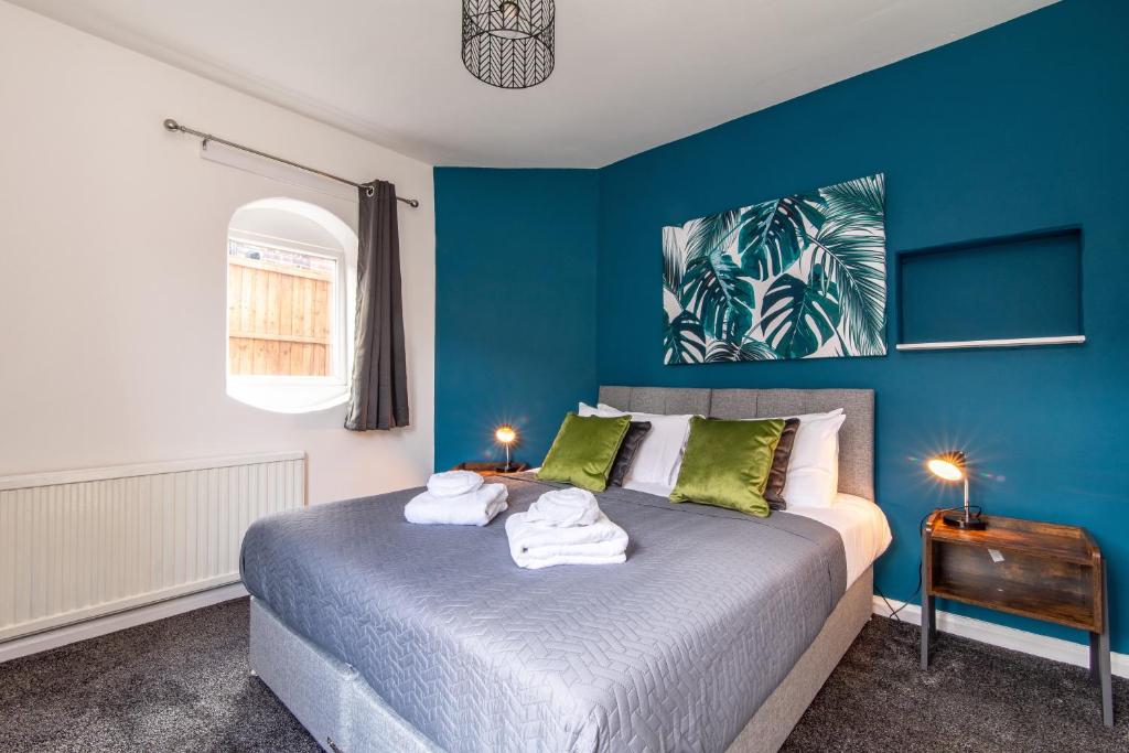 a blue bedroom with a bed with towels on it at Newly Refurbished Homely 4BR in Sherwood in Nottingham
