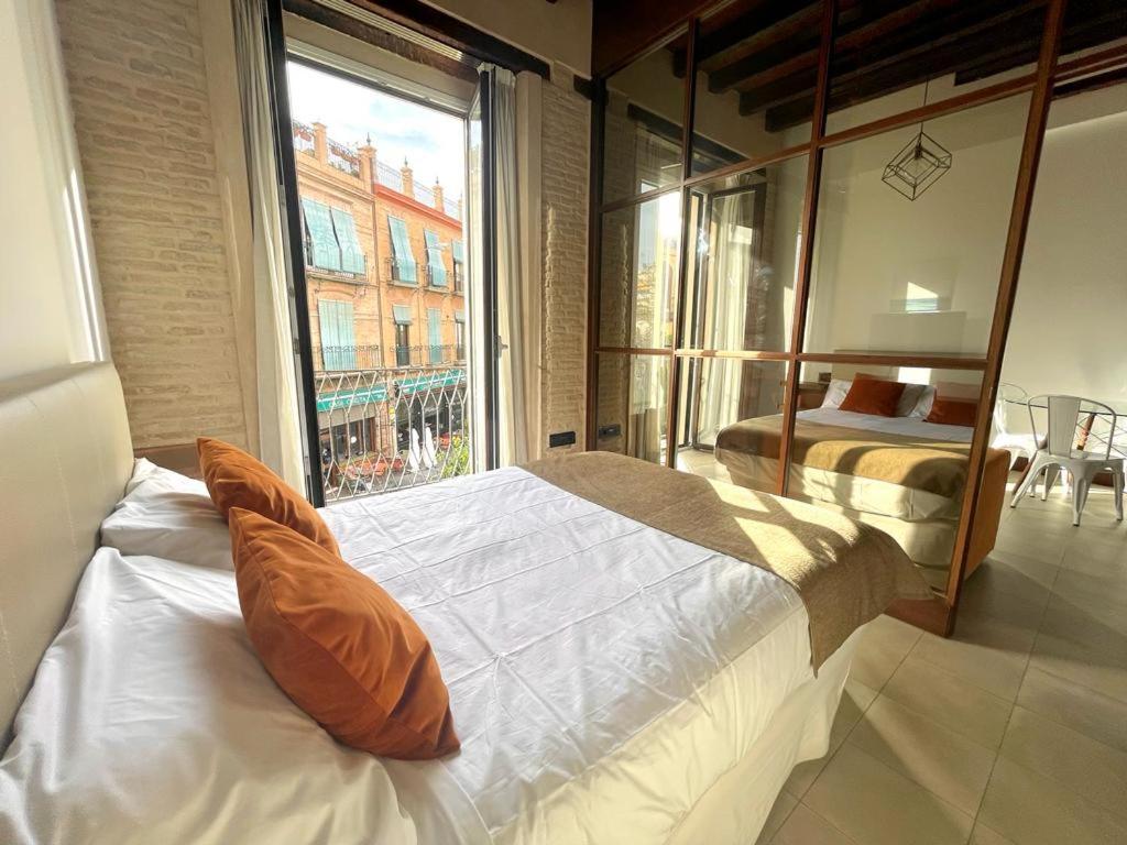 a bedroom with two beds and a large window at Eva Recommends Triana in Seville
