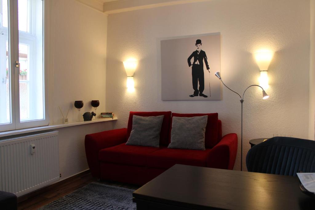 een woonkamer met een rode bank en een foto van een man bij Ferienwohnung im Alten Peter in Goslar