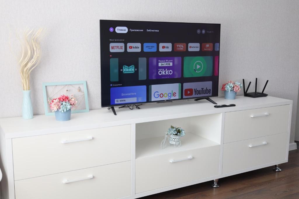 een tv op de top van een wit entertainment center bij Люкс в центре Караганды in Karagandy