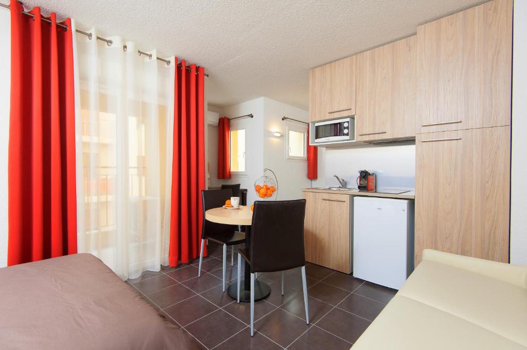 a small kitchen with red curtains and a table in a room at Villa Serafina Apartements in Nice