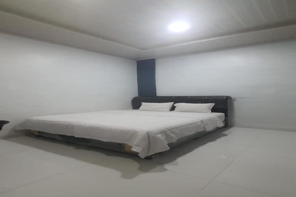 a bedroom with a bed in a white room at SPOT ON 92481 Modena Homestay Syariah in Medan