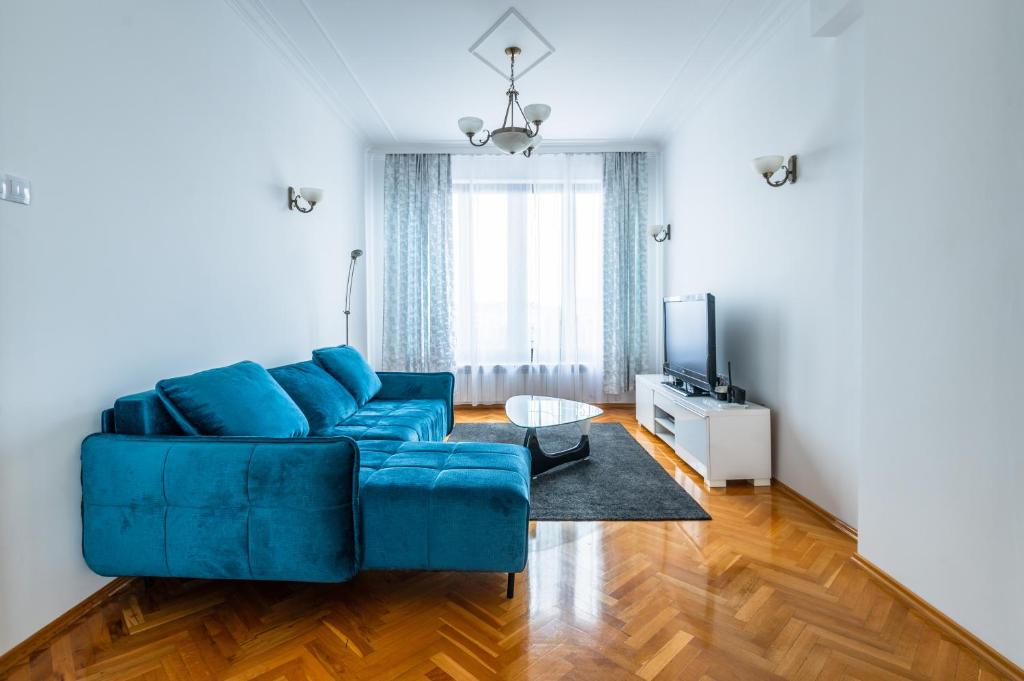 a living room with a blue couch and a television at Vitosha Str 2BD White & Blue Apt in Sofia