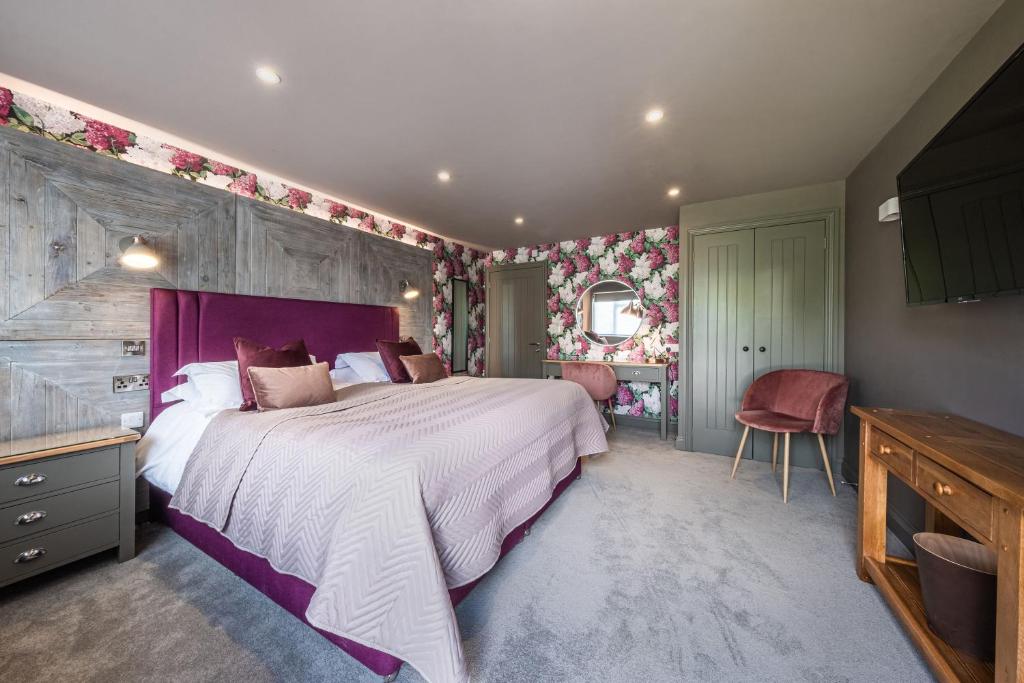 Schlafzimmer mit einem großen Bett mit einem lila Kopfteil in der Unterkunft The Cricketers Clavering in Clavering