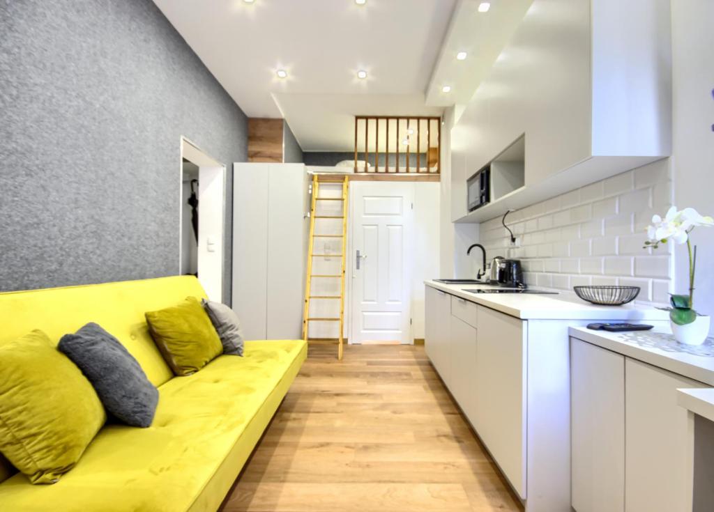 a living room with a yellow couch in a kitchen at Studio Mini Apart 6.2 - ACCO RENT in Gdańsk