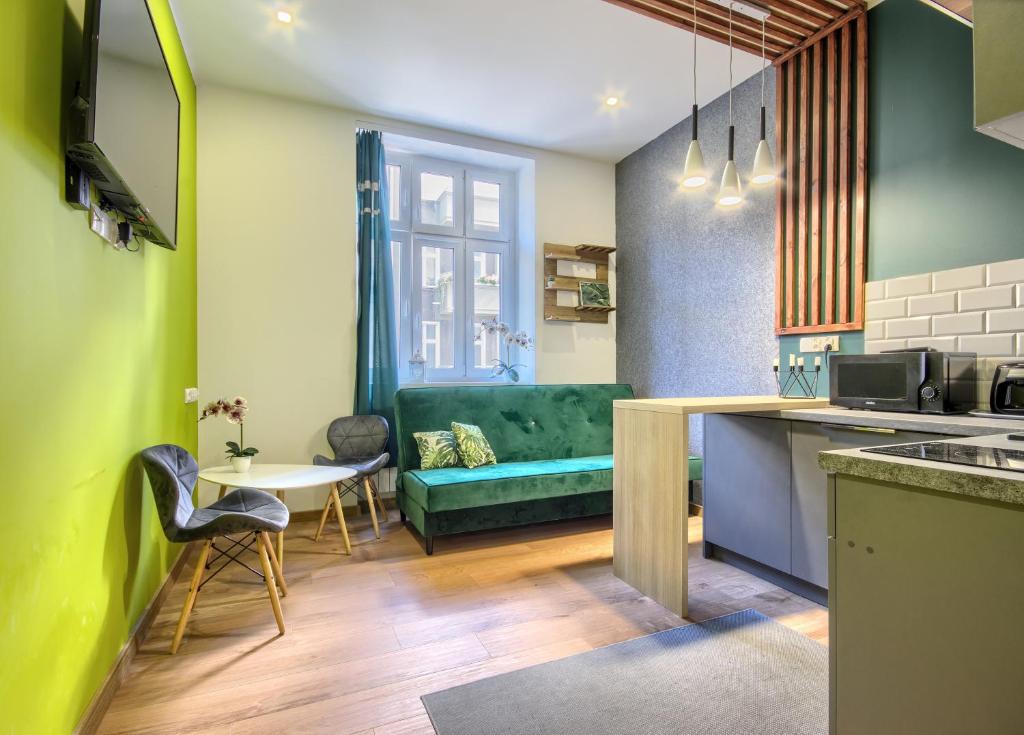 een keuken en een woonkamer met een groene bank bij Studio Mini Apart 6.3 - ACCO RENT in Gdańsk